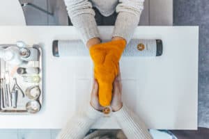 woman finishing her manicure with orange towel